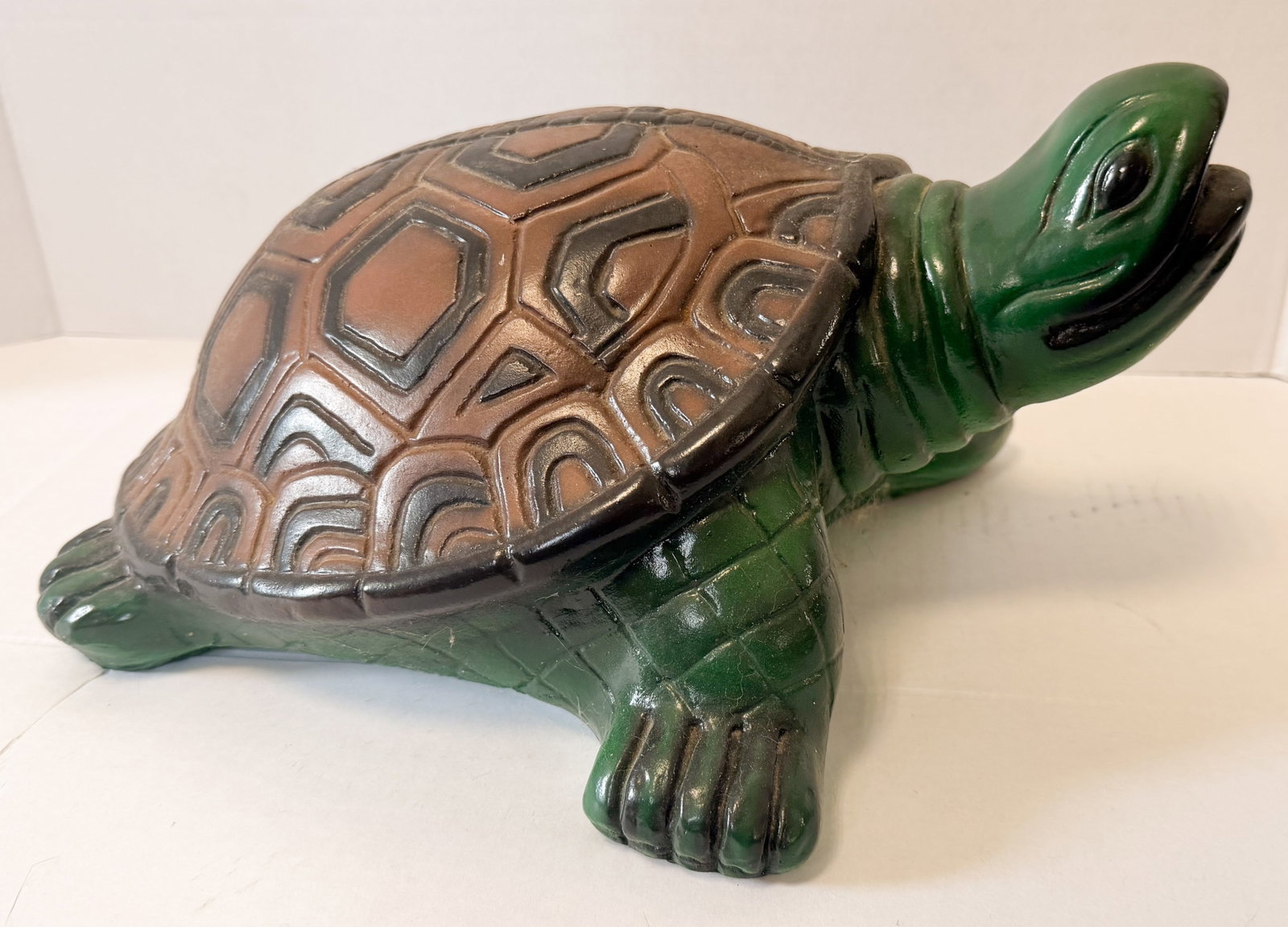 GLAZED CONCRETE TURTLE FIGURINE: turtle figurine modeled in a dynamic pose with an elevated head and open mouth. The object is finished in a high-gloss glaze with a green body and a multi-toned brown carapace.