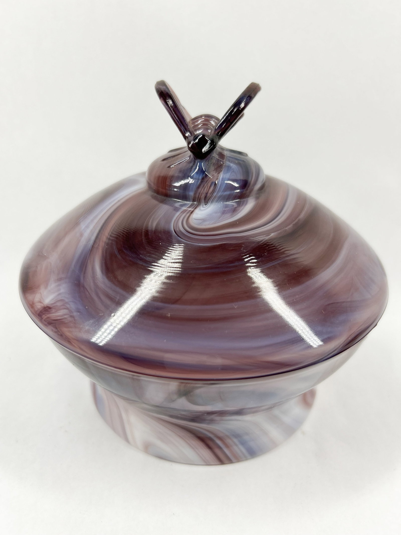 IMPERIAL PURPLE SLAG GLASS BEE DISH, 20TH CENTURY: An Imperial Glass Corporation purple slag glass honey dish featuring a molded bee finial. The interior rim bears a blue and silver oval foil label printed with a crown and stylized script reading Impe
