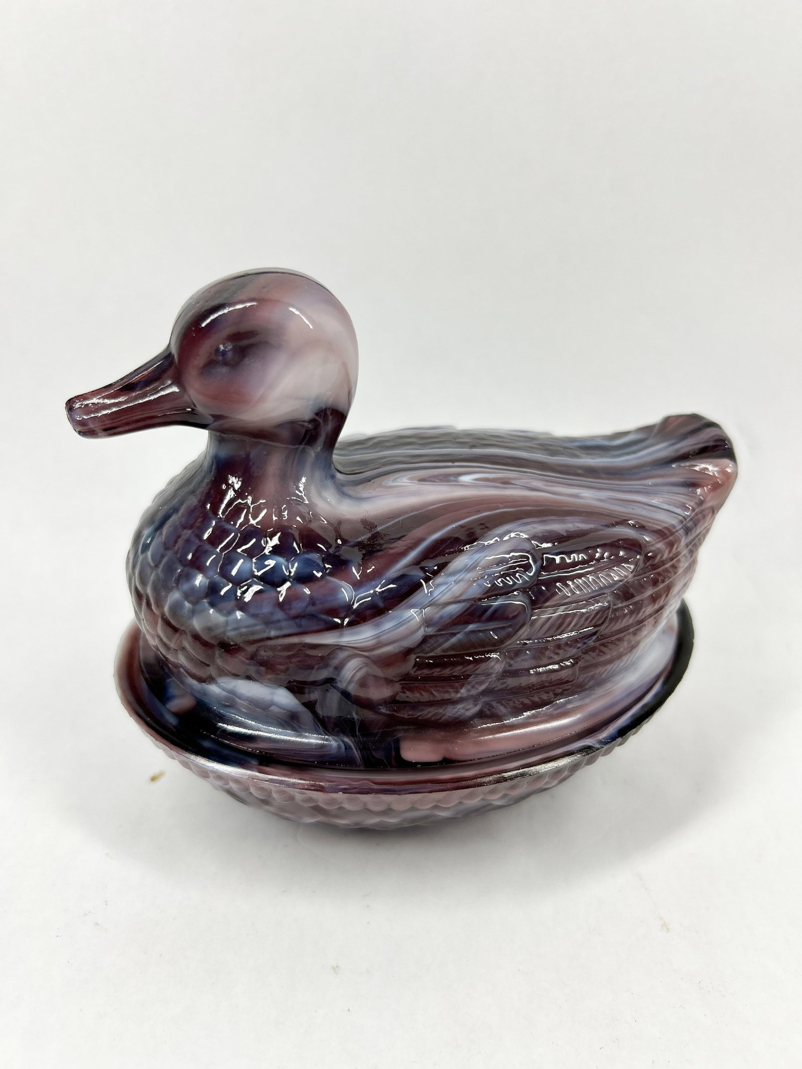 IMPERIAL PURPLE SLAG GLASS DUCK: Two-piece covered duck dish produced by Imperial Glass Corporation in purple slag glass featuring a basketweave textured base. An original blue and white adhesive label is visible on the interior base