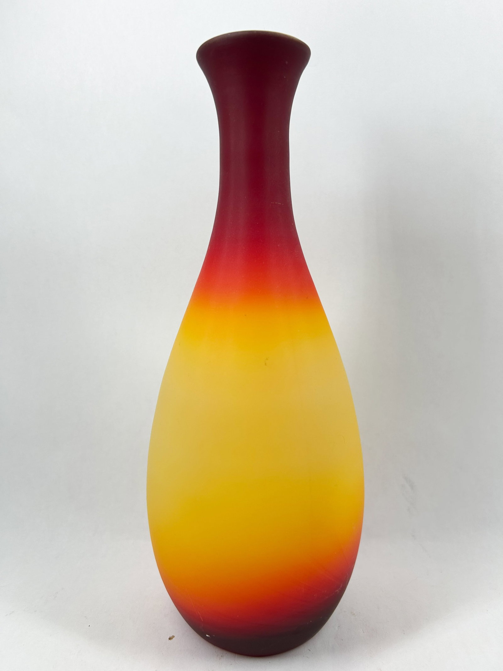 IMPERIAL SATIN PEACHBLOW VASE, CIRCA 1970: Hand-blown cased glass vase featuring a tri-color gradient from red to yellow with a matte satin finish. The vessel is constructed with an opaque white interior casing and displays no visible signatur
