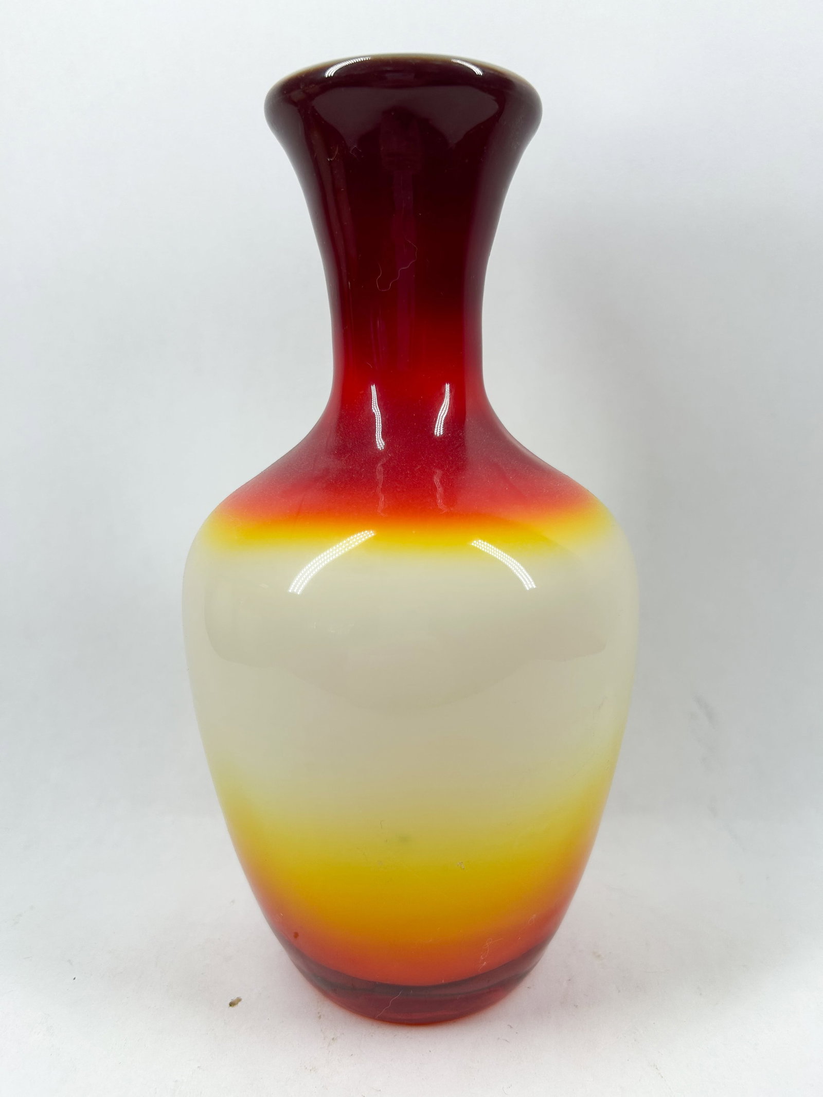 IMPERIAL PEACHBLOW VASE, 1960S: Mid-century modern hand-blown cased glass vase featuring a tri-color gradient from ruby to yellow over a white interior. The silhouette features a bulbous body and a flared rim.