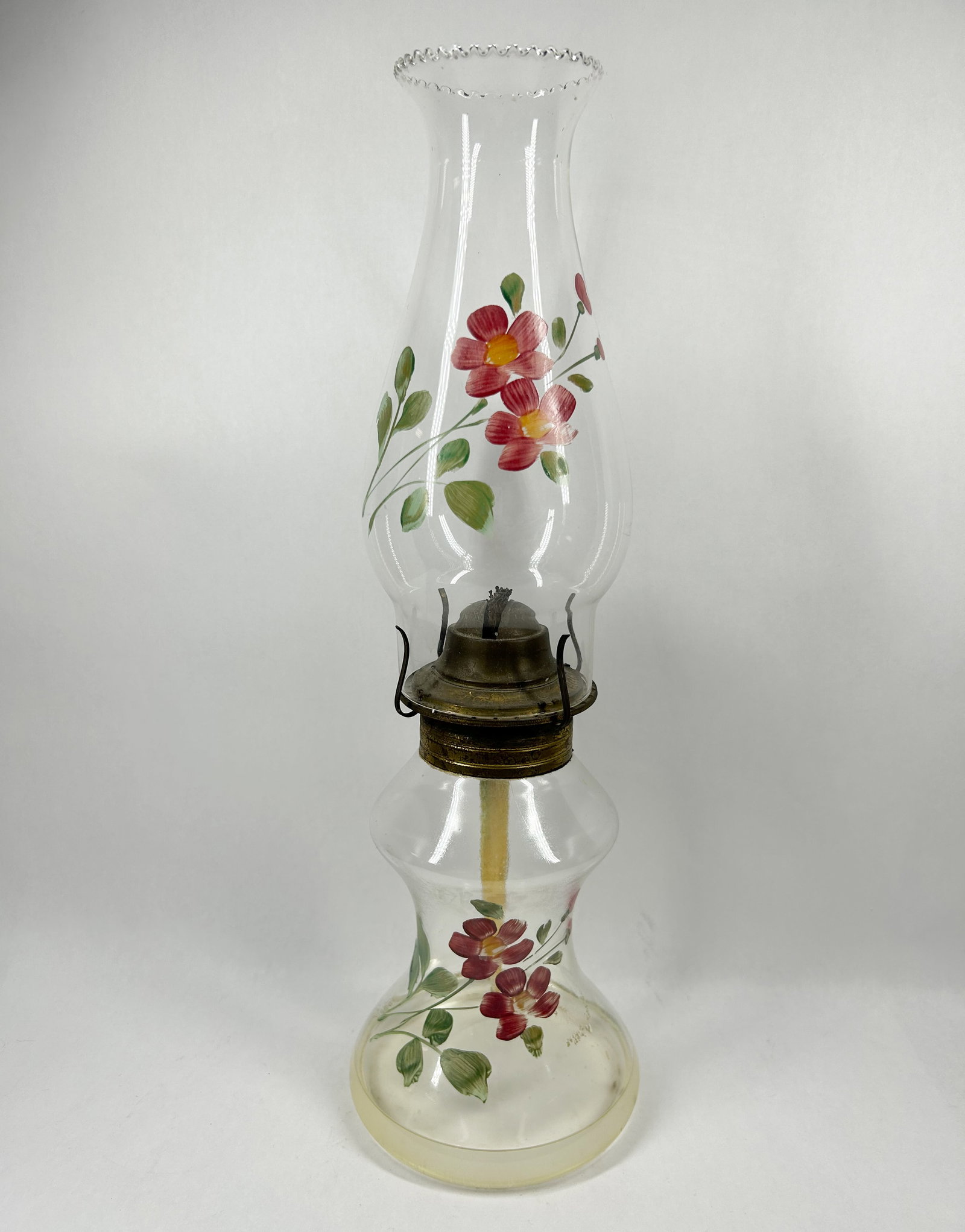 EAGLE VINTAGE HAND-PAINTED GLASS OIL LAMP: Vintage oil lamp constructed of clear glass with hand-painted polychrome floral decoration. The brass-toned metal burner assembly is embossed with the characters EAGLE.