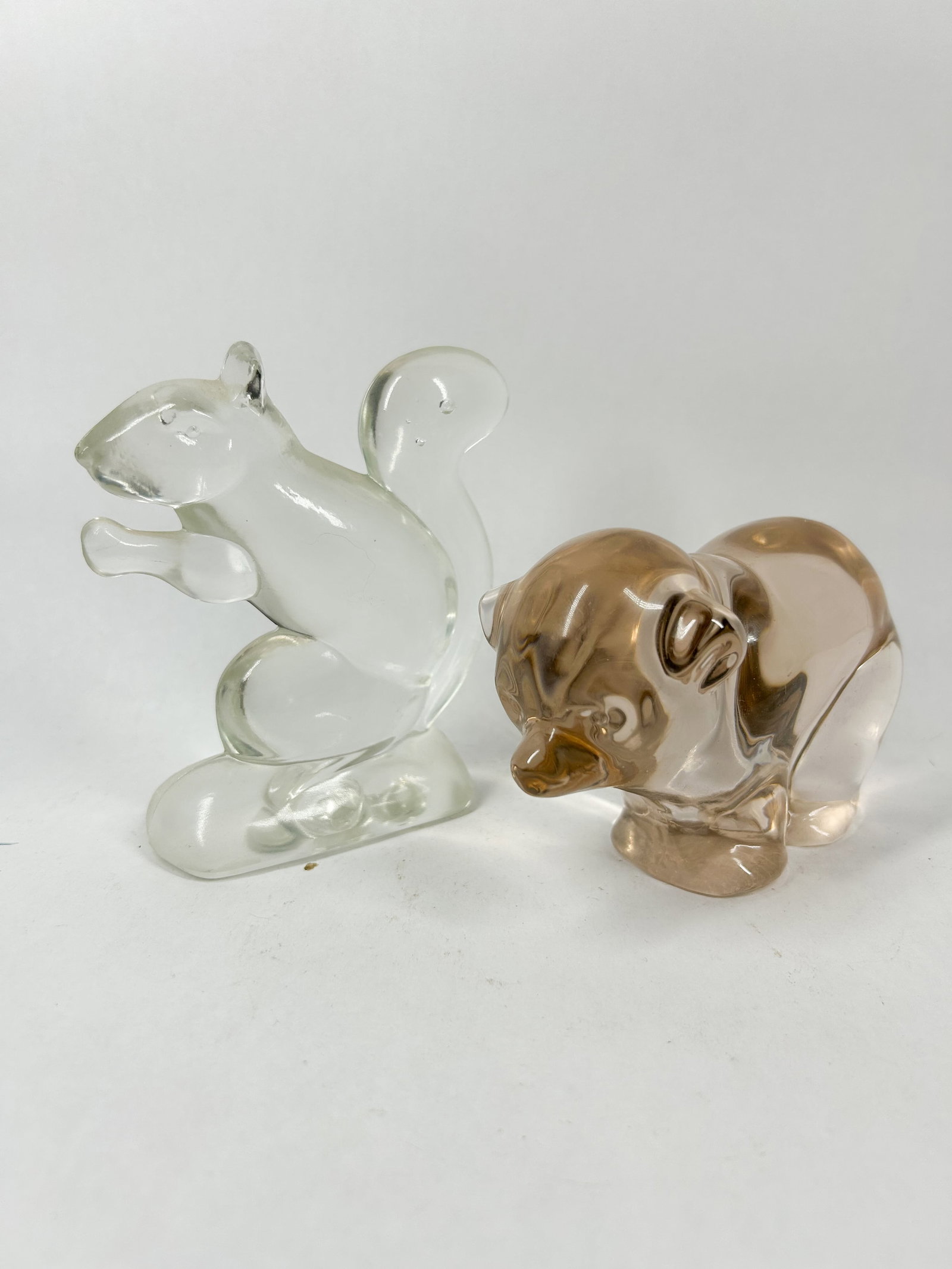 HEISEY GLASS ANIMAL FIGURINES: A pair of solid molded glass figurines including a squirrel in clear crystal and a bear cub in transparent smoky brown glass. The squirrel features an embossed mark on the underside of the base consis