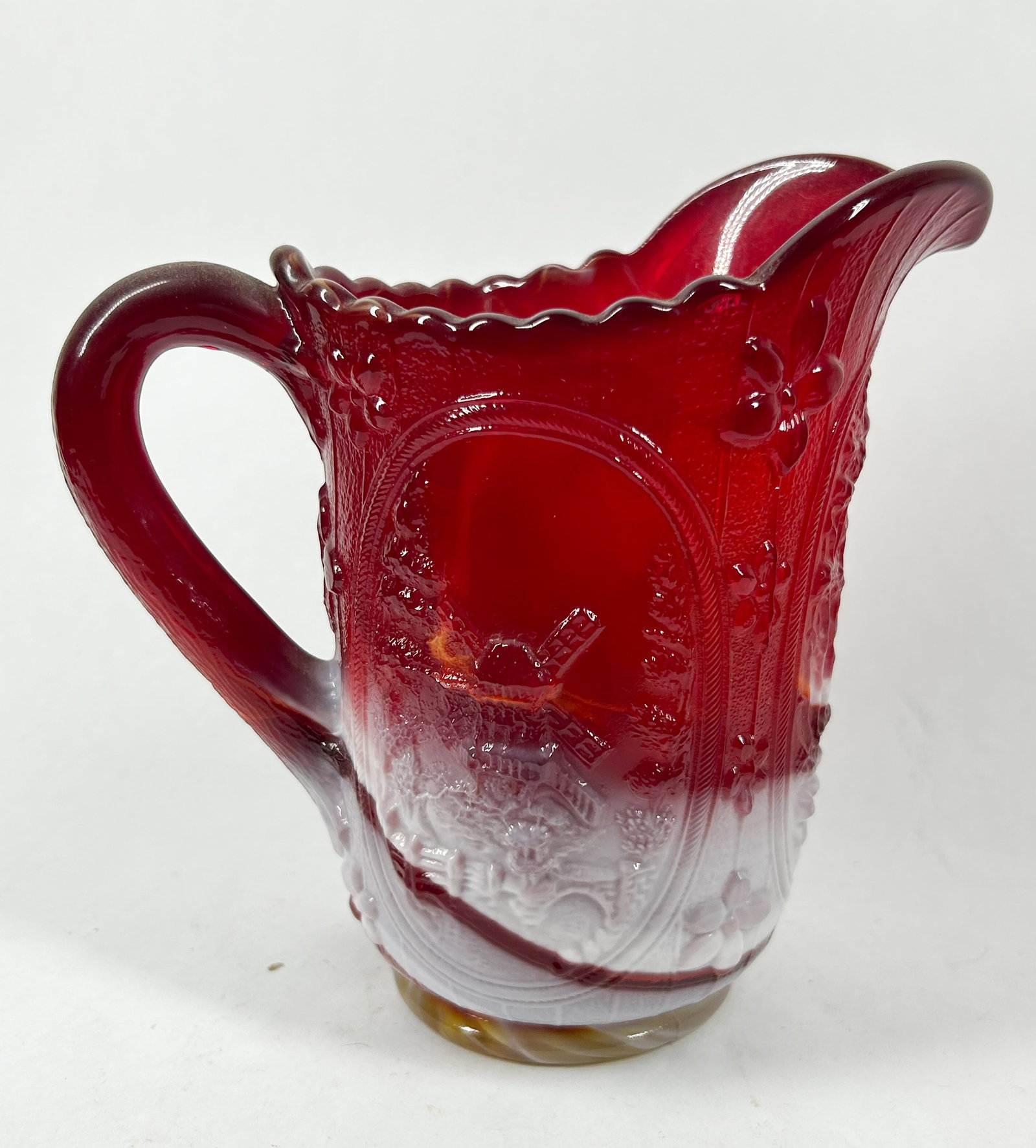 IMPERIAL RUBY SLAG GLASS PITCHER, CIRCA 1970: Pressed ruby red and white slag glass pitcher in the Windmill and Wreathed Cherry pattern. An embossed G mark within a circle is present on the interior base.