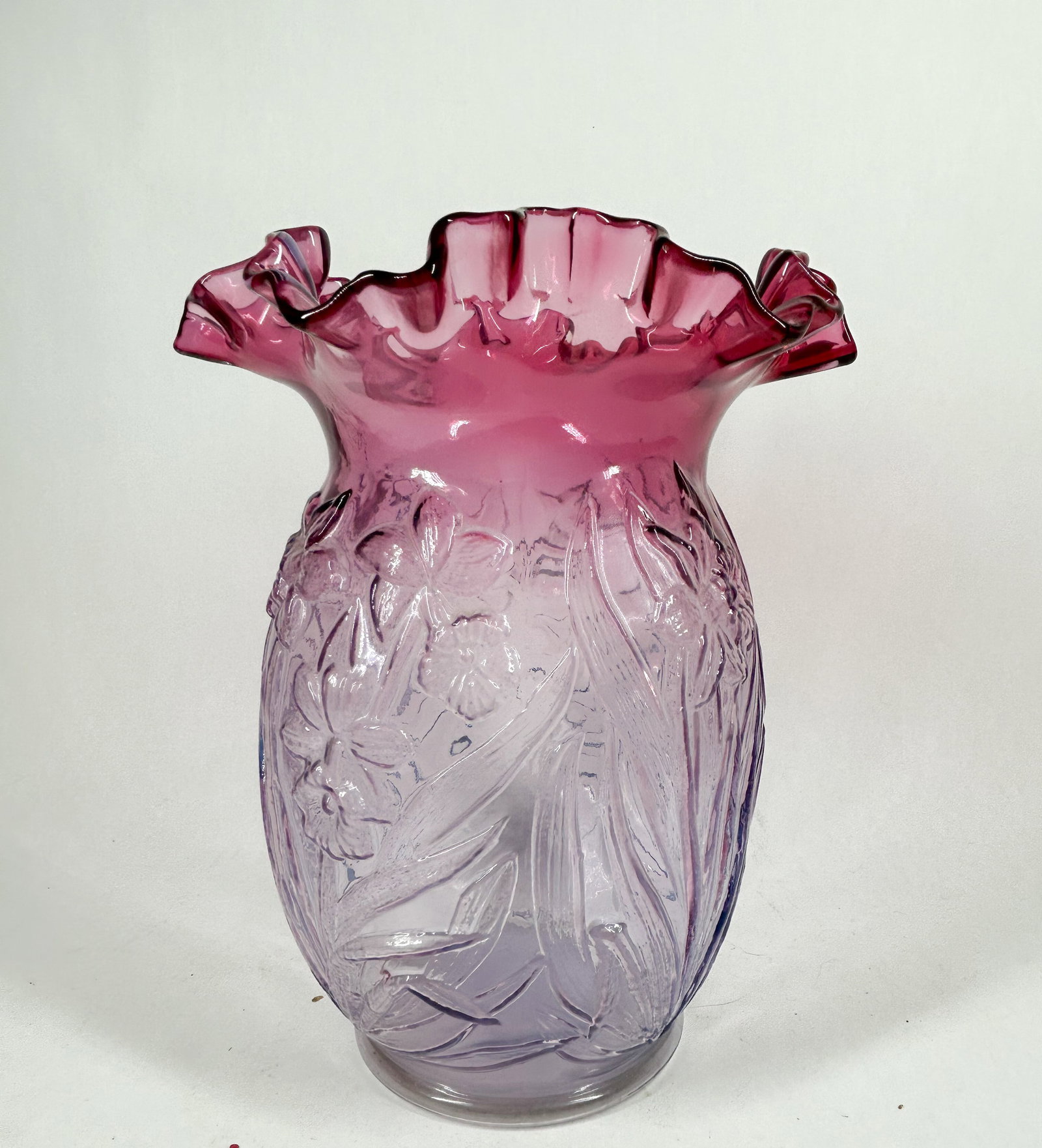 FENTON DAFFODIL GLASS VASE, 1990S: Fenton Art Glass pressed glass vase featuring a molded floral daffodil motif and a hand-crimped ruffled rim. The piece transitions from cranberry to lavender and bears an embossed mark on the base