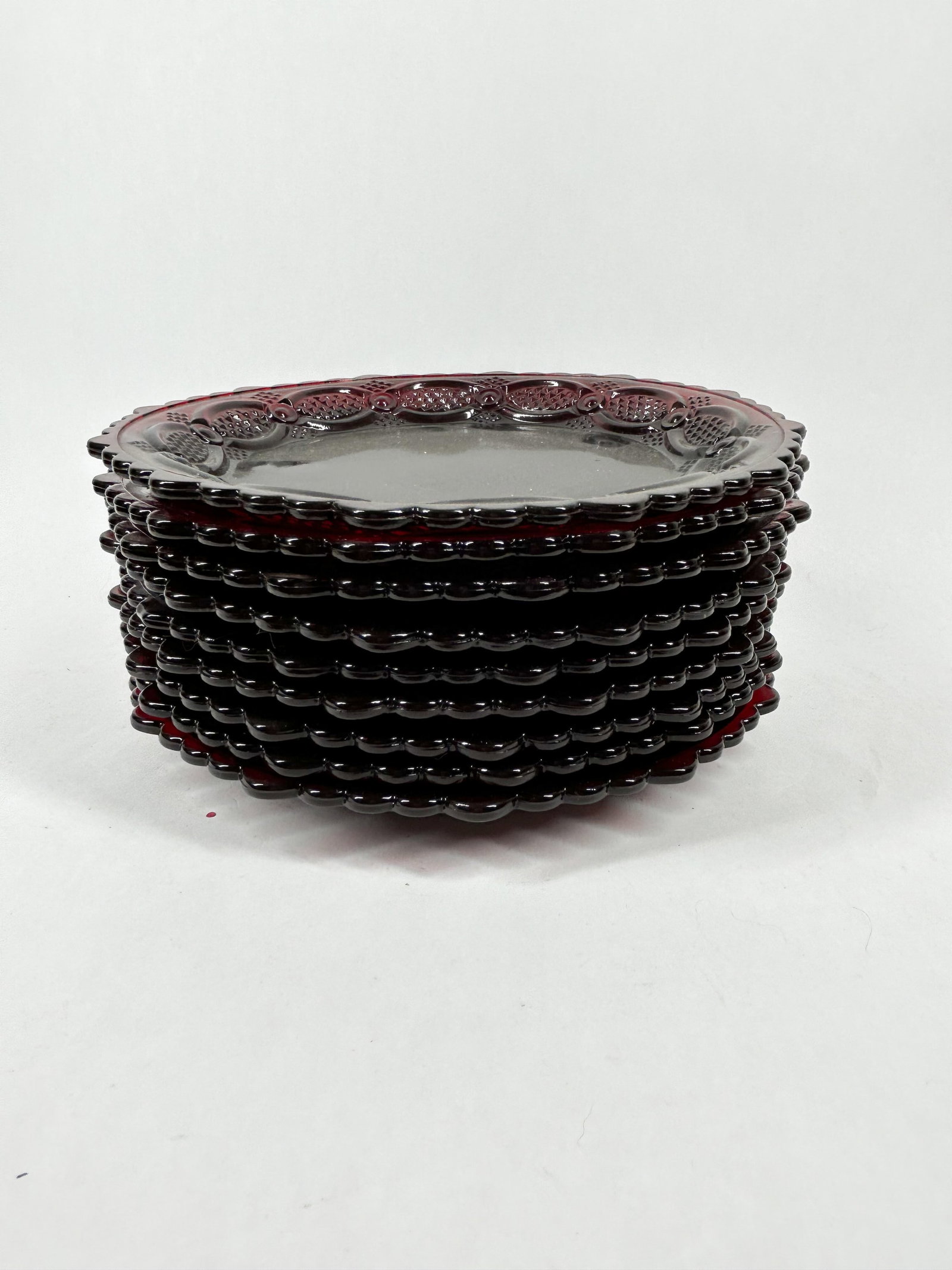 AVON RUBY RED SALAD PLATES, 1970S: A set of ten Avon ruby red pressed glass salad plates in the 1876 Cape Cod pattern. Each plate features an embossed mark reading AVON on the underside rim.