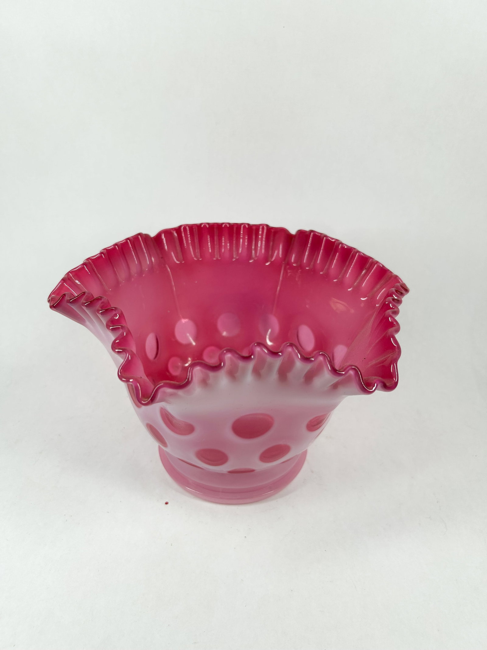 FENTON CRANBERRY OPALESCENT COIN DOT BOWL: A mid-20th century cranberry opalescent glass bowl featuring an all-over coin dot pattern and a ruffled rim. The vessel sits on an integral circular pedestal base with no maker's marks or signatures