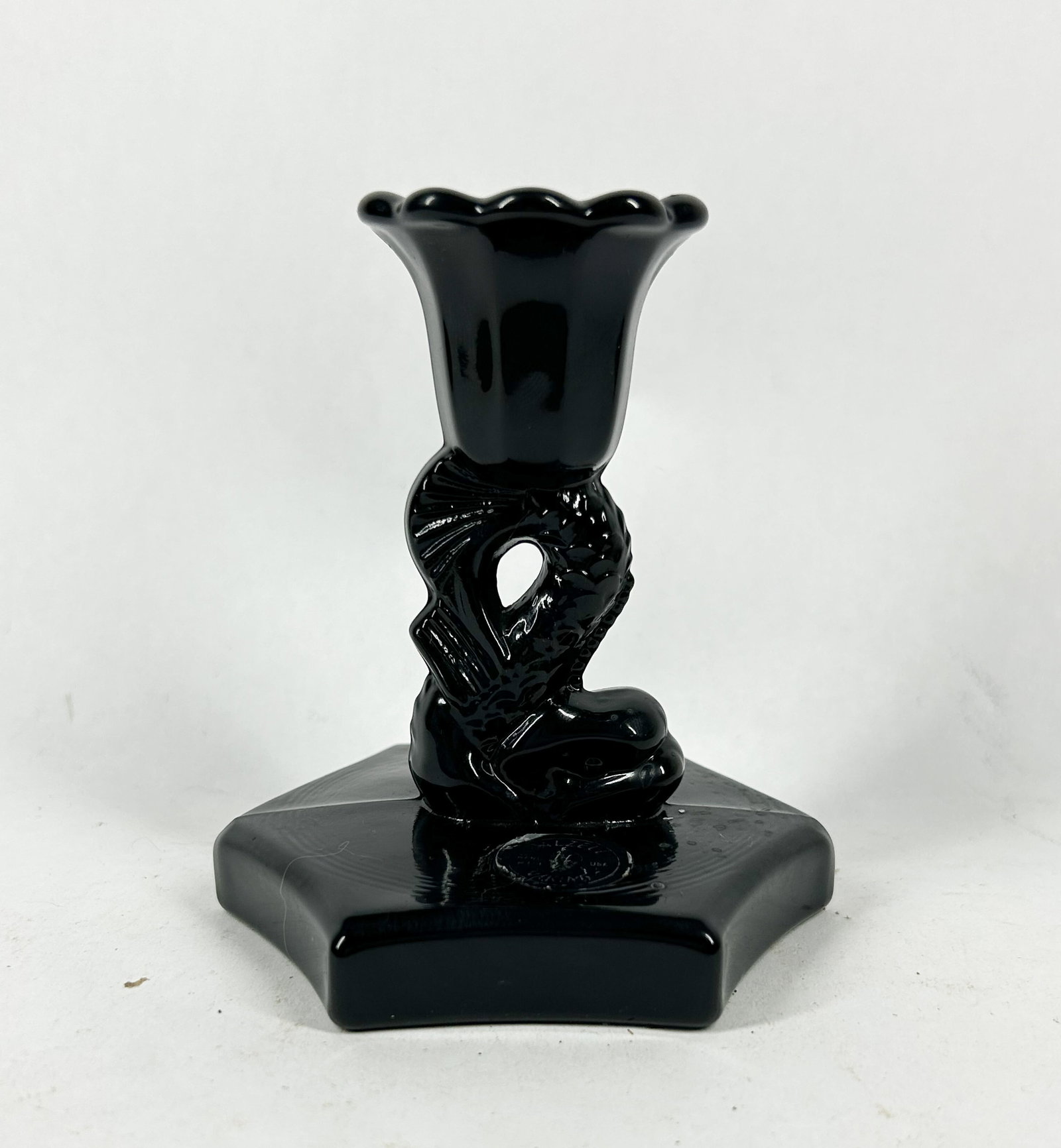 DALZELL VIKING BLACK GLASS CANDLESTICK, C. 1990: A Dalzell Viking black pressed glass candlestick featuring a stylized dolphin stem and a scalloped tulip-form cup above an embossed circular mark on the hexagonal base reading DALZELL and VIKING