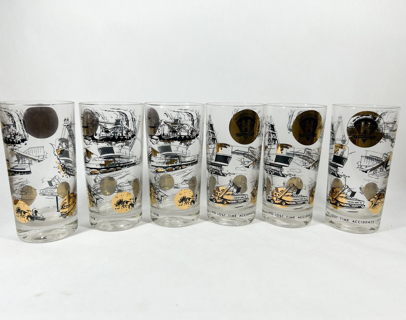 CONSOLIDATION COAL CO. GLASS TUMBLERS, 1957-1959: A set of clear glass tumblers featuring black and gold-tone enameled graphics commemorating industrial safety achievements from 1957 to 1959. Each tumbler is decorated with a printed gold-tone