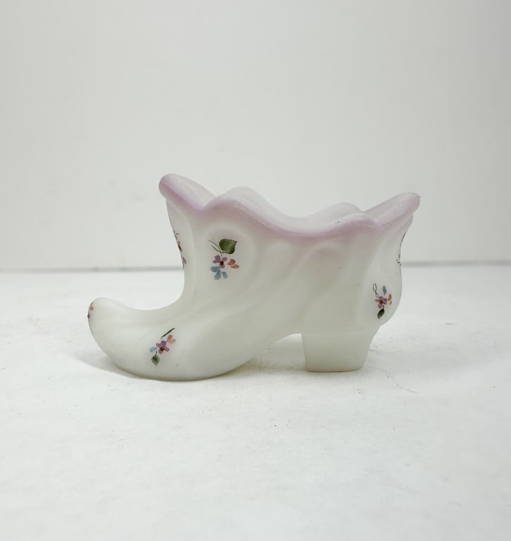 FENTON SATIN GLASS SLIPPER VINTAGE: A Fenton Art Glass Company slipper crafted in white satin milk glass with hand-painted floral motifs. An adhesive silver oval label on the base is printed with a stylized script letter F inside an ova