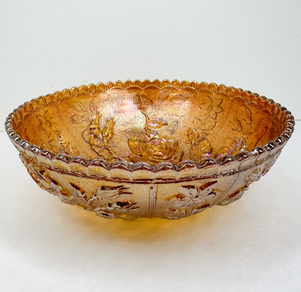 MARIGOLD CARNIVAL GLASS ROSE BOWL: A large pressed carnival glass bowl featuring a relief-molded floral pattern and a marigold iridescent finish. No maker's mark or labels are visible on the base or body.