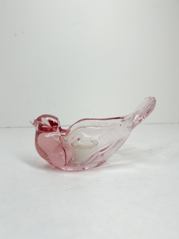 PINK GLASS BIRD VOTIVE HOLDER: Translucent pink glass votive candle holder in the form of a stylized bird. The figurine features a molded body with a central circular well and an upward-sweeping ribbed tail.