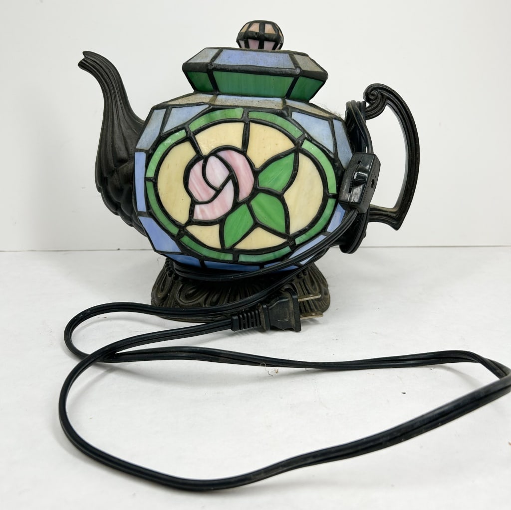 CHEYENNE STAINED GLASS TEAPOT LAMP: A Chinese-made stained glass accent lamp produced by Cheyenne, featuring circular panels with pink rose motifs. The base retains a white adhesive label printed with the maker name and an oval gold foi