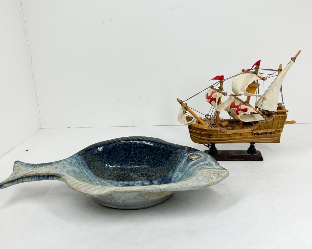KUHA STUDIO POTTERY DISH AND MODEL SHIP: This lot features a fish-shaped glazed stoneware dish by Kuha and a wooden model of a Spanish-style sailing ship. The ceramic dish is formed with an integral tail handle and incised details, finished 
