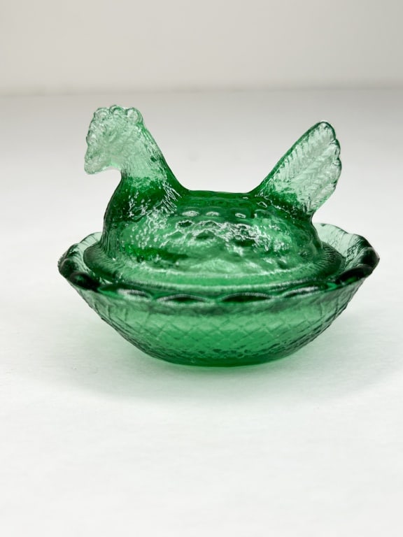 EMERALD GREEN GLASS MINI HEN ON NEST: A two-piece press glass miniature hen on nest salt cellar in emerald green. The piece features a stylized nesting hen cover over a basket-weave textured base with a scalloped lacy rim. No marks or lab