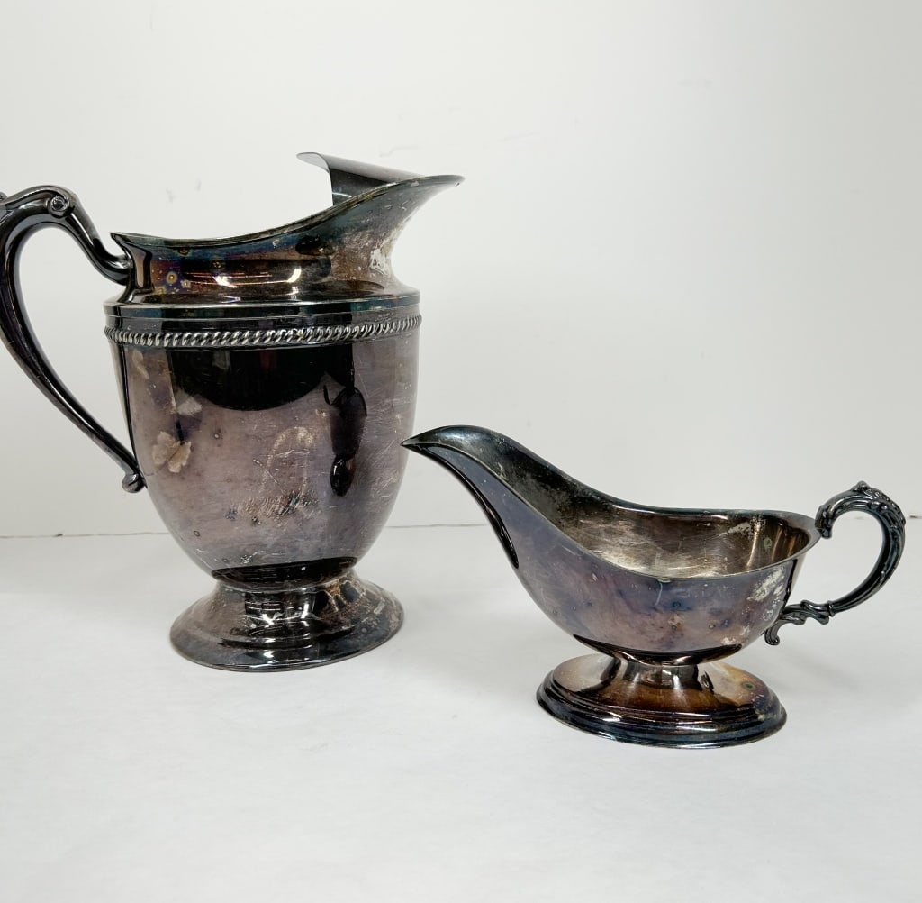 WILCOX SILVER PLATE PITCHER AND SAUCE BOAT: A silver-plated water pitcher and matching sauce boat manufactured by the Wilcox Silver Plate Co. The underside of the pitcher base features two lines of text and four rectangular cartouches: the top 