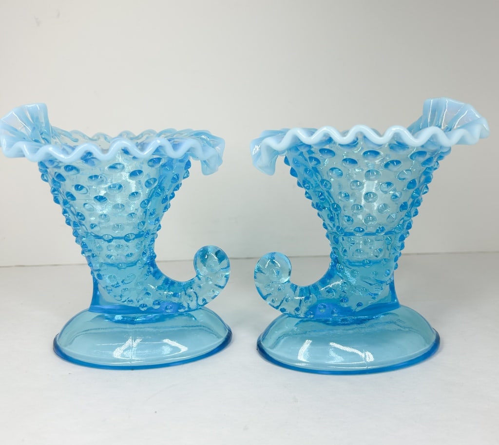 PAIR OF BLUE OPALESCENT HOBNAIL CORNUCOPIA VASES: A pair of pressed glass cornucopia vases in blue opalescent glass. Each vase features a ruffled rim with milky white opalescence and a body decorated with a repeating hobnail pattern, mounted on a smo