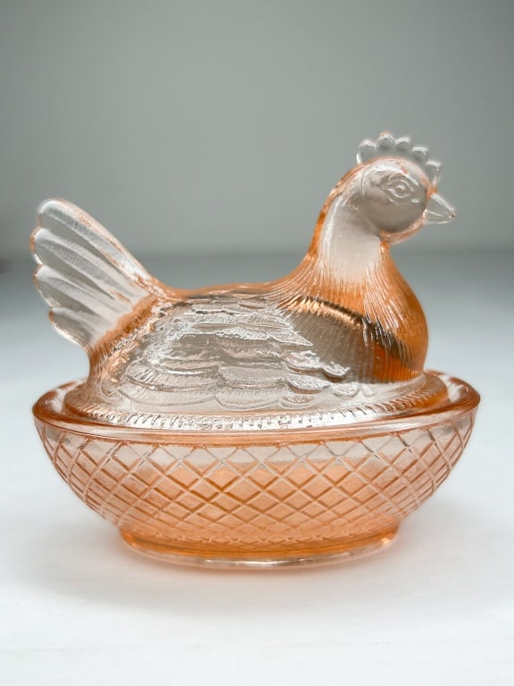 BOYD PINK URANIUM GLASS HEN ON NEST: A vintage pressed glass lidded dish in the form of a hen on a nest, executed in peach-pink glass with uranium content. The base features a diamond-shaped mark containing a letter B with a line above a