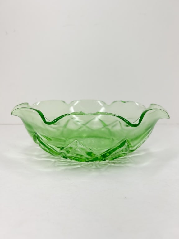 PRESSED URANIUM GLASS RUFFLED BOWL: A green pressed uranium glass bowl featuring a ruffled rim and geometric relief patterns. The design consists of a central 24-point starburst on the base surrounded by interlocking diamond and arched 