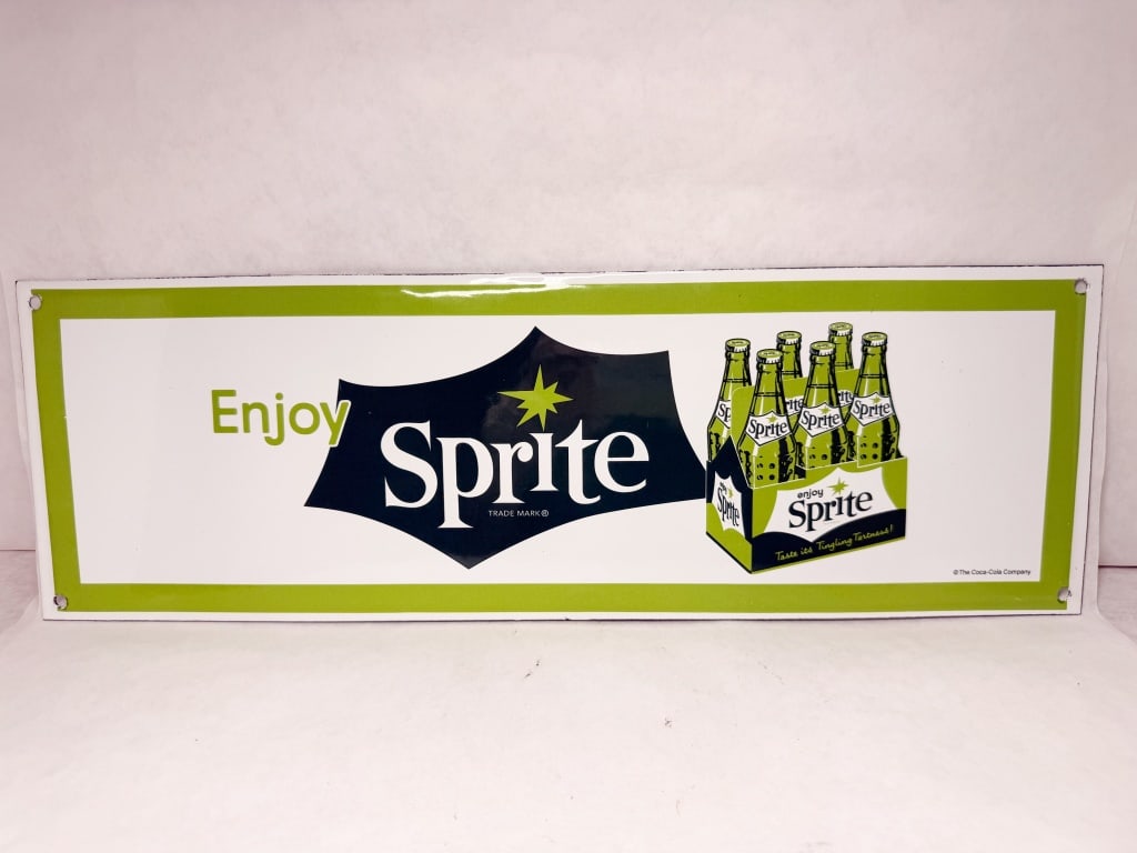 VINTAGE SPRITE METAL SIGN: A rectangular heavy-gauge metal advertising sign with a glossy white finish and green border produced for The Coca-Cola Company. The design features a stylized dark blue starburst containing the word 
