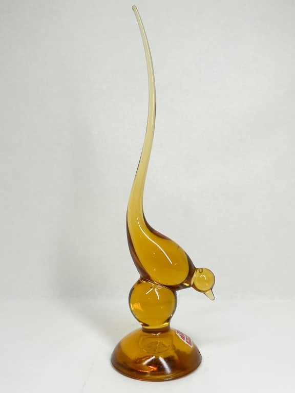 VIKING AMBER GLASS BIRD FIGURINE: Amber hand-blown glass bird figurine produced by Viking Glass for Gump's. The piece features a stylized avian form with a pulled-glass tail, resting on a spherical stem and circular base. A red and si