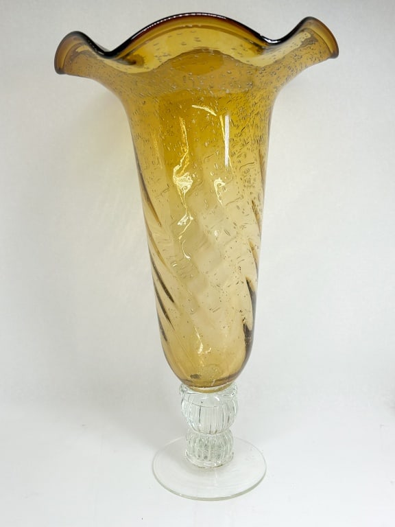 AMBER PULEGOSO GLASS RUFFLED VASE: A large hand-blown glass centerpiece vase featuring a honey-amber pulegoso body with a diagonal optic swirl. The vessel is joined to a clear glass pedestal base comprising a ribbed multi-knop stem on 