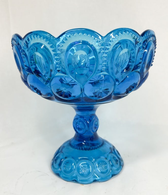 MOON AND STAR BLUE GLASS COMPOTE: Vintage pedestal compote in blue pressed glass featuring the Moon and Star pattern. The bowl is designed with a scalloped rim and sits on a matching patterned footed base.