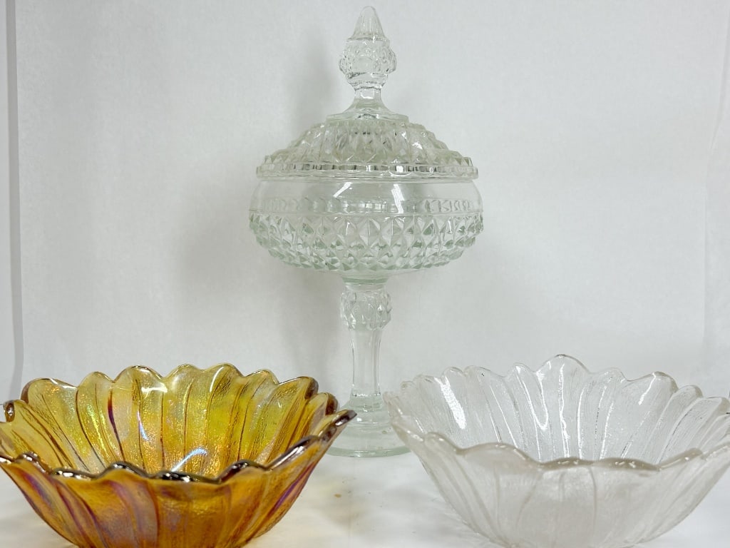 TRIO OF DECORATIVE AMERICAN GLASSWARE: A collection of decorative pressed glass comprising a pedestaled covered candy dish in a diamond point pattern and a pair of scalloped bowls with vertical optic ribs and sunflower medallions. One