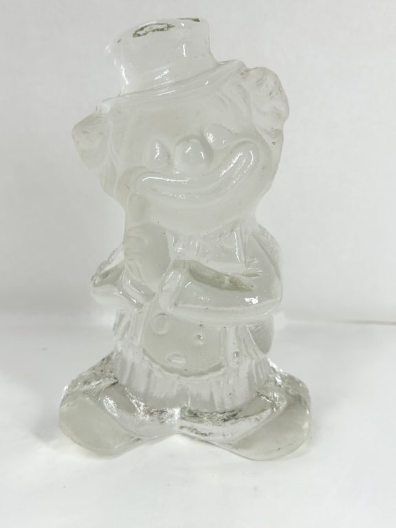 VINTAGE CLEAR PRESSED GLASS CLOWN FIGURINE: A vintage clear pressed glass figurine depicting a smiling clown in a top hat and oversized suit. The figure features a textured frosted finish to the face and hands, with an opening at the top of
