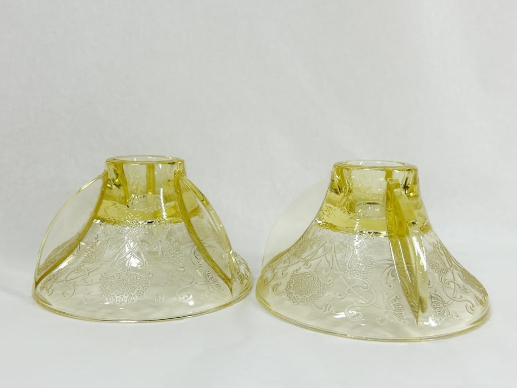 PAIR OF FLORENTINE POPPY YELLOW GLASS CANDLESTICKS: A pair of yellow depression glass candlesticks in the Florentine pattern, also known as Poppy. Each features a flared base with three integrated vertical fins and an etched floral scrollwork design. A