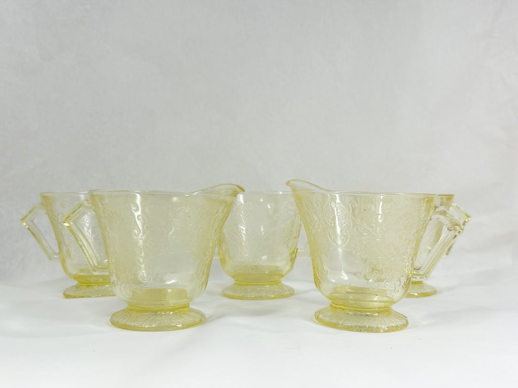 FIVE PIECES OF FLORENTINE DEPRESSION GLASS: A set of five yellow Depression glass service pieces consisting of two creamers and three open sugar bowls. Each vessel is decorated with a pressed floral and scroll motif known as the Florentine or P