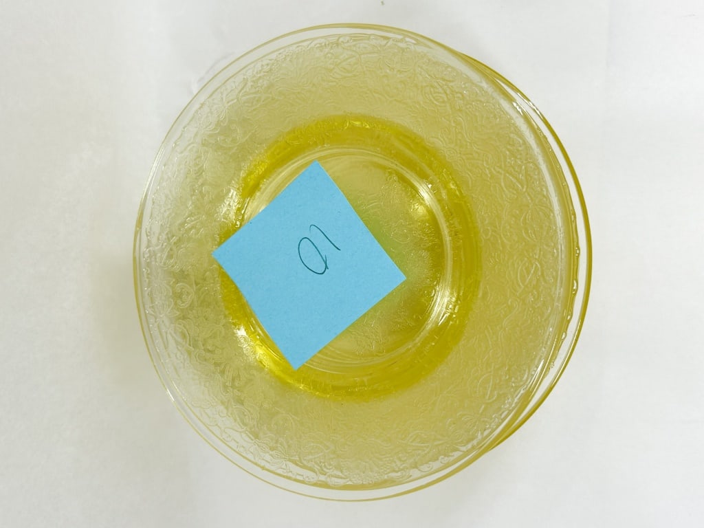 SET OF YELLOW DEPRESSION GLASS PLATES: A set of ten yellow depression glass plates featuring an intricate acid-etched foliate and floral scrolling border and a central floral medallion. The translucent canary yellow glass displays a smooth