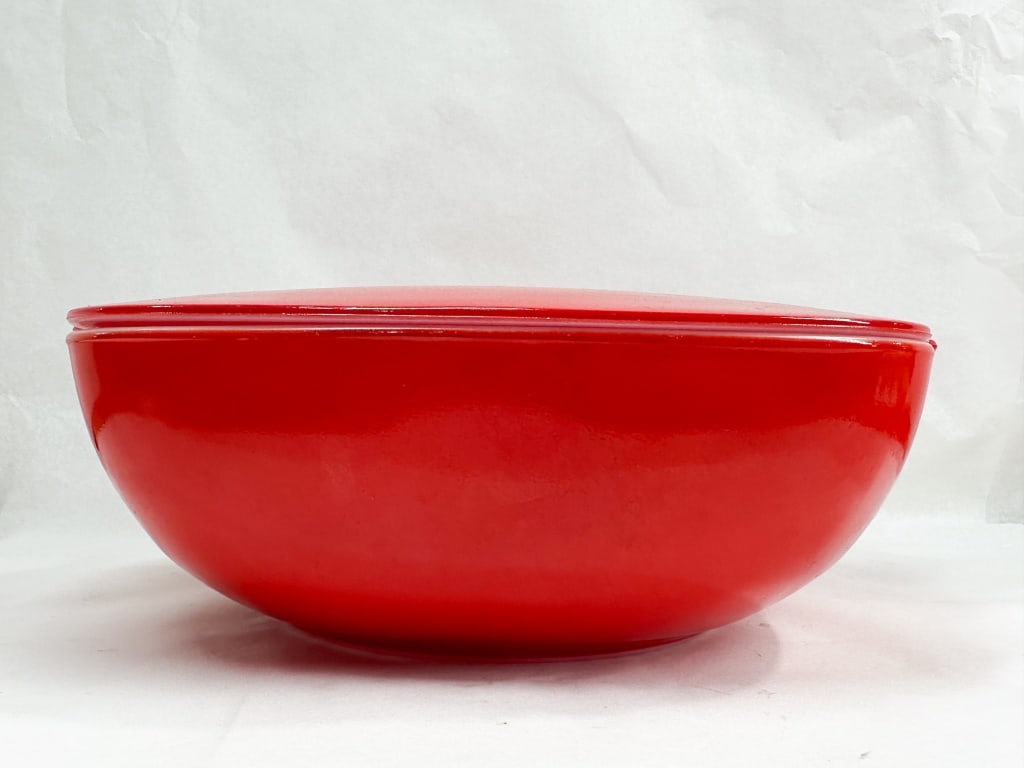 RED GLASS CASSEROLE DISH AND LID: A mid-century modern covered casserole dish featuring a square-to-round form with integrated tab handles. The vessel is constructed of white milk glass with a fired-on red exterior finish and includes