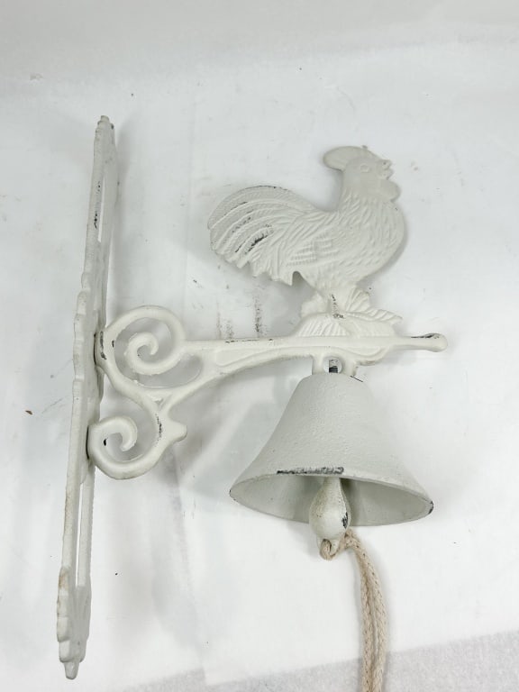 CAST IRON ROOSTER WALL BELL: A wall-mounted decorative dinner bell in sand-cast iron featuring a figural rooster finial perched atop a scrolled horizontal bracket. The conical bell is suspended by a threaded bolt and eyelet, cont