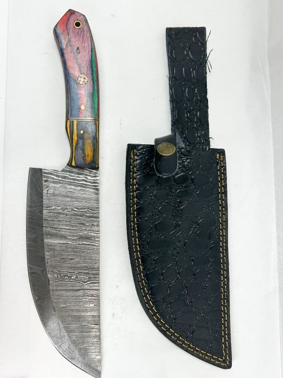 DAMASCUS STEEL CLEAVER WITH LAMINATE HANDLE: Fixed blade cleaver constructed from pattern-welded Damascus steel featuring a full tang and decorative file work along the spine. The handle consists of multi-colored dyed wood laminate scales secure