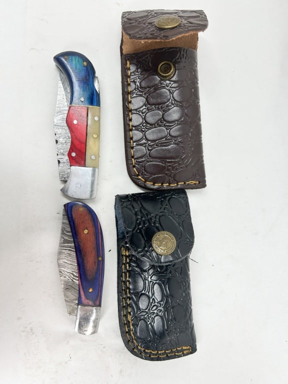 TWO DAMASCUS STEEL FOLDING KNIVES: Two single-blade folding pocket knives featuring pattern-welded Damascus steel blades. One knife features a multi-part handle composed of blue-dyed wood, red-dyed wood, and white bone scales with deco