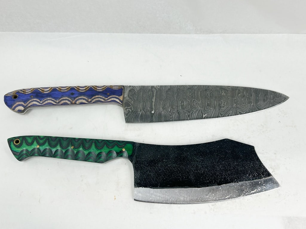 TWO CUSTOM DAMASCUS AND TOOL STEEL KNIVES: Two handmade fixed-blade knives including a chef's knife and a cleaver. The chef's knife features a pattern-welded Damascus steel blade and a blue and natural laminated wood handle; the cleaver is con