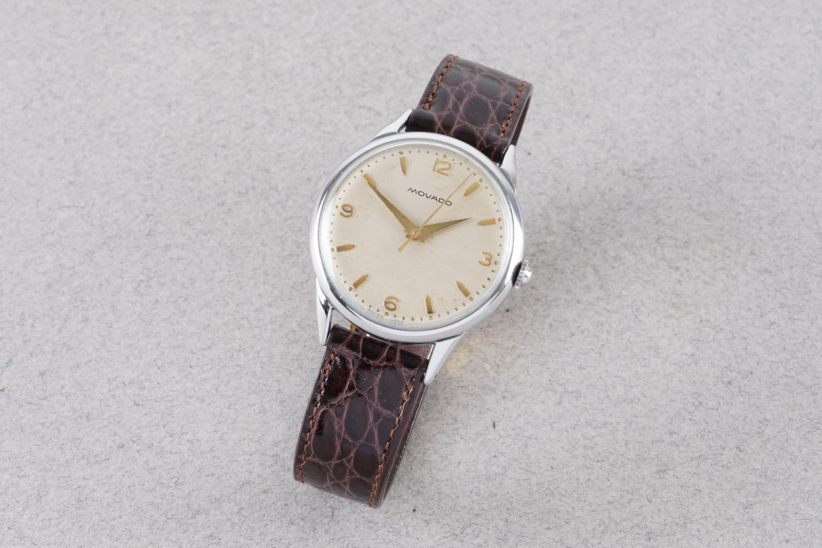 MOVADO DRESS WRISTWATCH REF. 38302: MOVADO DRESS WRISTWATCH REF. 38302, this watch is a ref. 38302 and is fitted with a circular off white dial with hour markers and hands. The 34mm stainless steel case is fitted with a crown and a snap