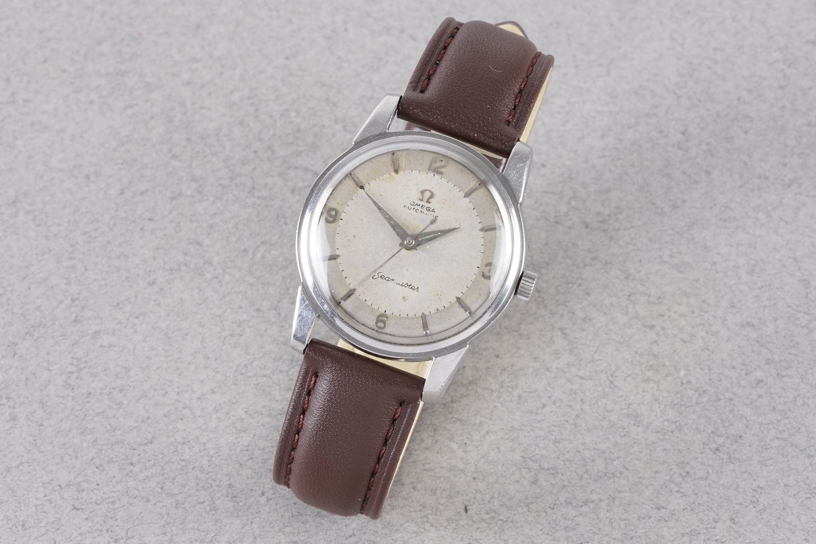 OMEGA SEAMASER AUTOMATIC WRISTWATCH: OMEGA SEAMASER AUTOMATIC WRISTWATCH, this watch is fitted with a circular patina dial with hour markers and hands. The 34mm stainless steel case is fitted with a crown and a case back. Inside is an au