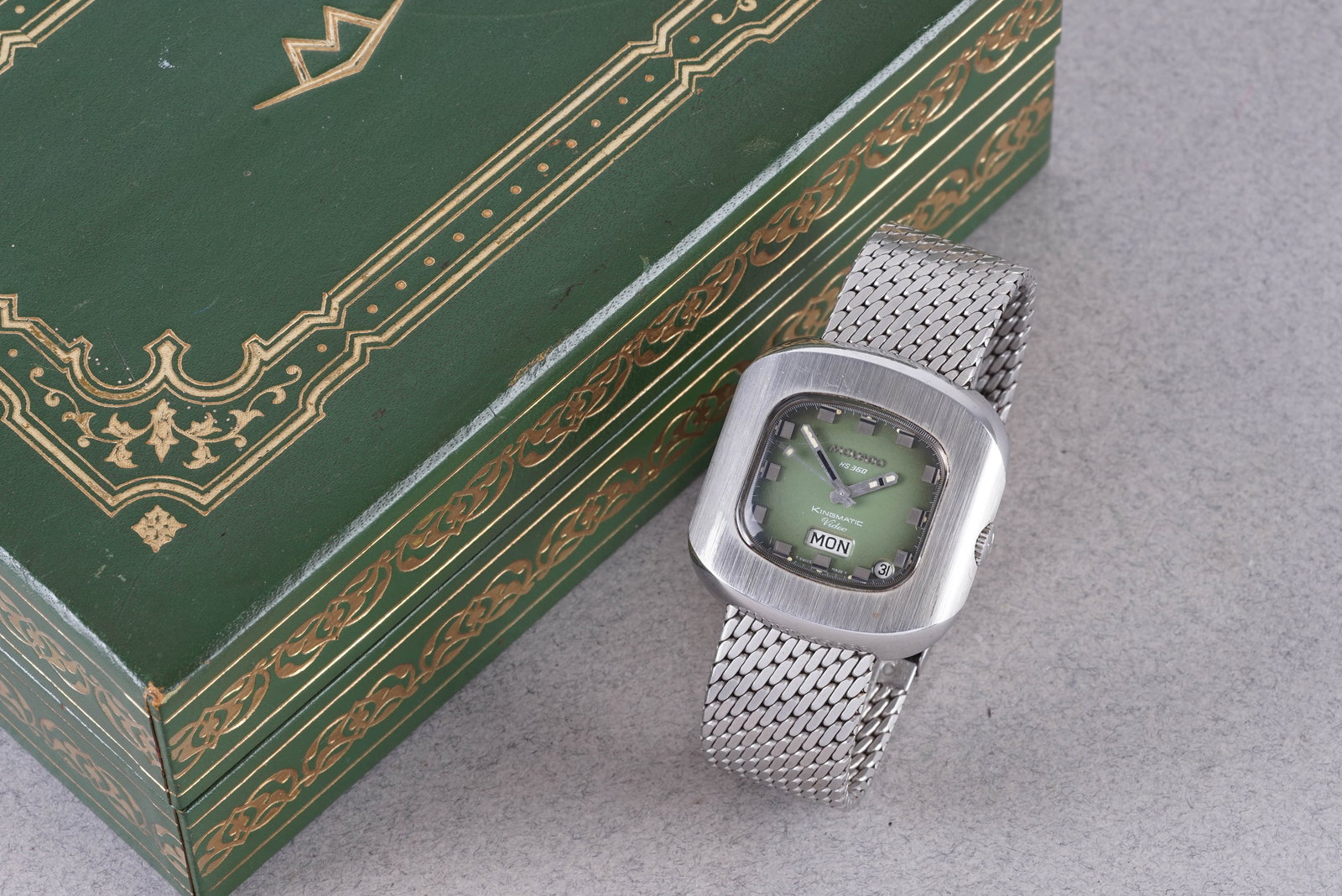 MOVADO H 360 KINGMATIC VIDEO DAY DATE W/ BOX: MOVADO H 360 KINGMATIC VIDEO DAY DATE W/ BOX, this watch is fitted with a rounded green dial with day date windows, hour markers and hands. The stainless steel case is fitted with a crown and a