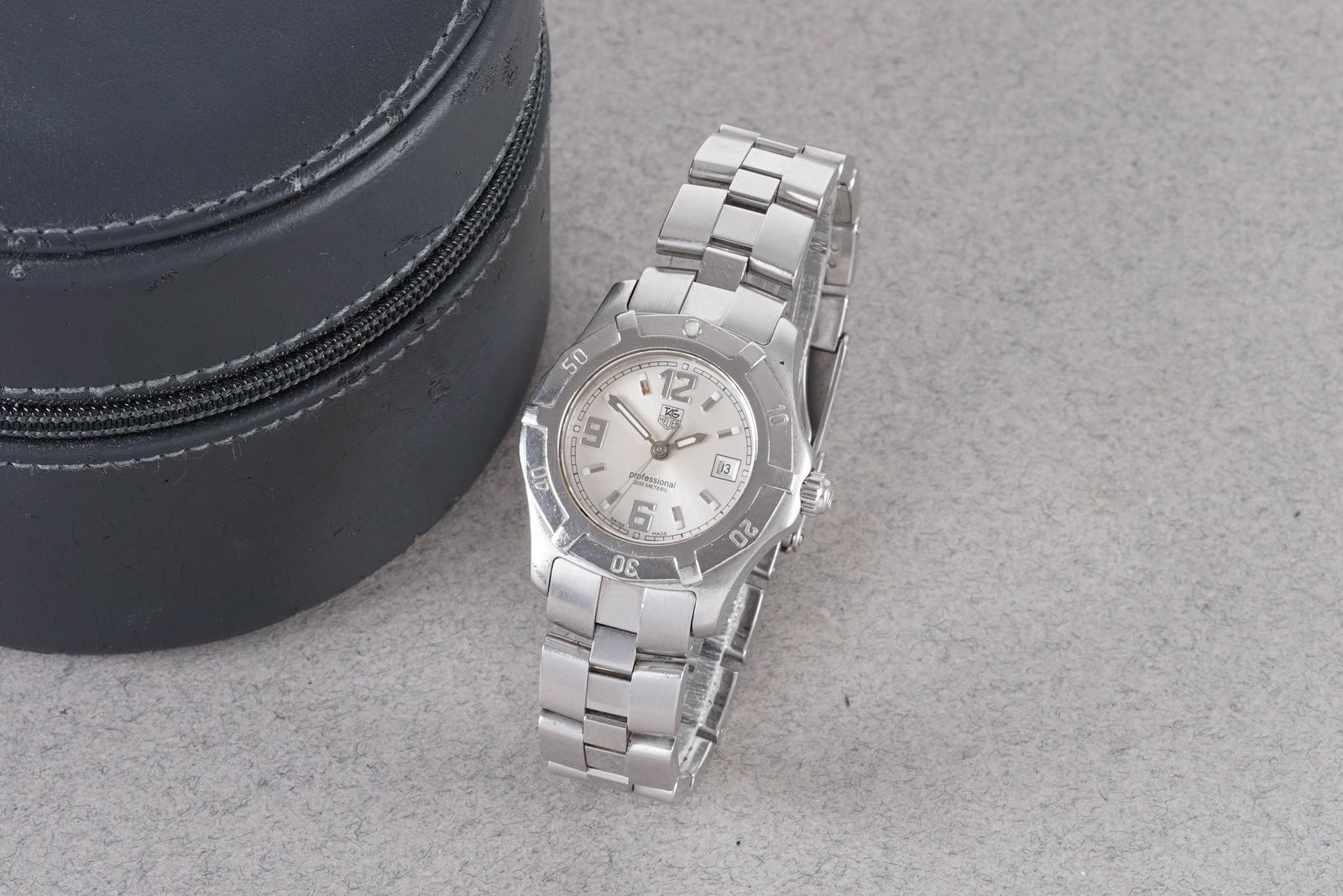TAG HEUER PROFESSIONAL DATE W/ CASE REF. WN131C: TAG HEUER PROFESSIONAL DATE W/ CASE REF. WN131C, this watch is a ref. WN131C and is fitted with a circular silver dial with a date window, hour markers and hands. The 33mm stainless steel case is fitt