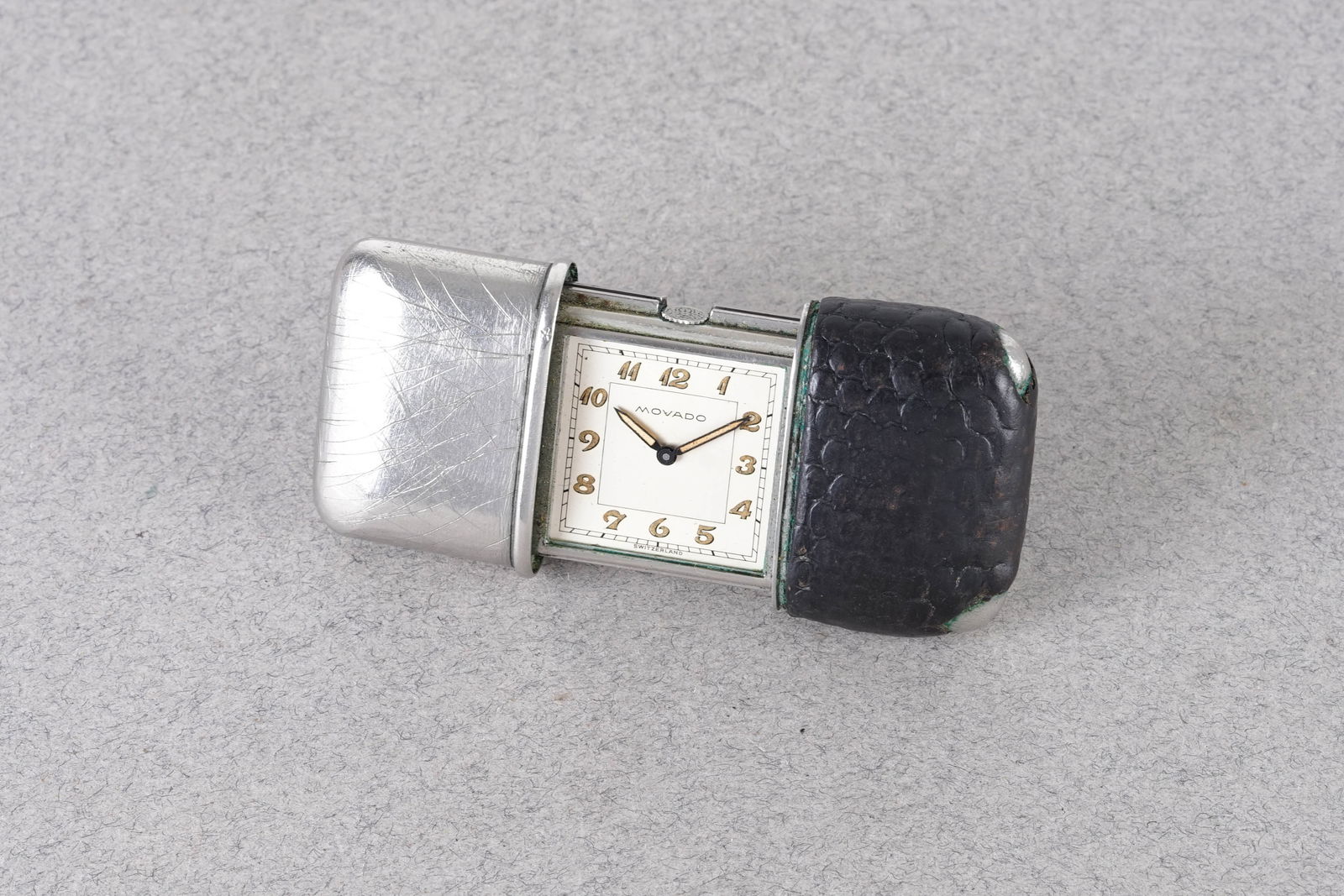 MOVADO ERMETO TRAVEL WATCH: MOVADO ERMETO TRAVEL WATCH, this watch is fitted with a square two tone silver dial with breguet numeral hour markers and pencil hands. The 70x30mm case is fitted with leather on one side of the closi