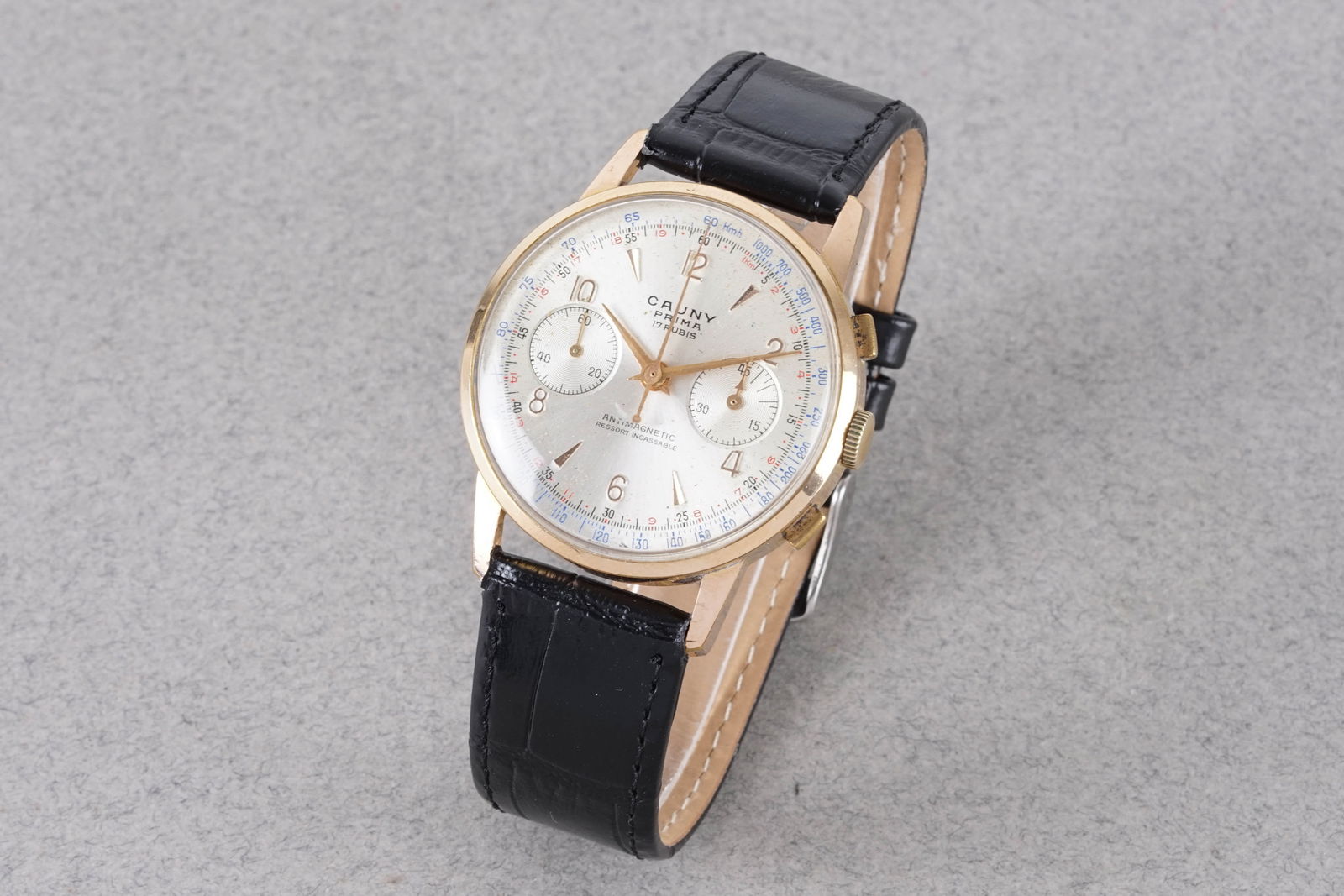 CAUNY PRIMA GOLD PLATED CHRONOGRAPH: CAUNY PRIMA GOLD PLATED CHRONOGRAPH, this watch is fitted with a circular twin register dial with arrow head and arabic numeral hour markers and hands. The 37mm gold plated case is fitted with a