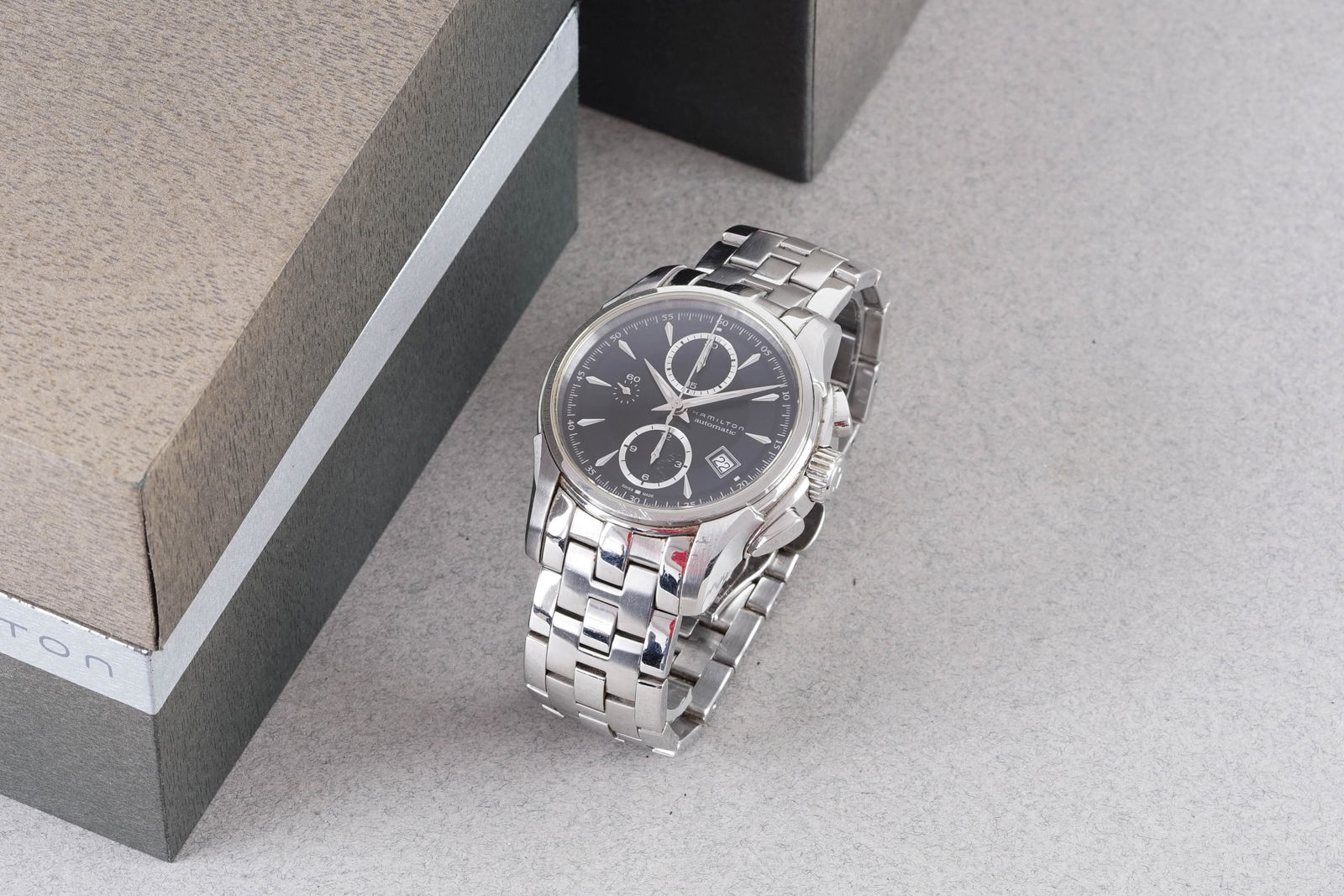 HAMILTON JAZZMASTER AUTOMATIC DATE CHRONOGRAPH W/ BOX REF. H326160: HAMILTON JAZZMASTER AUTOMATIC DATE CHRONOGRAPH W/ BOX REF. H326160, this watch is a ref. H326160 and is fitted with a circular black twin register dial with hour markers and hands. The 43mm stainless