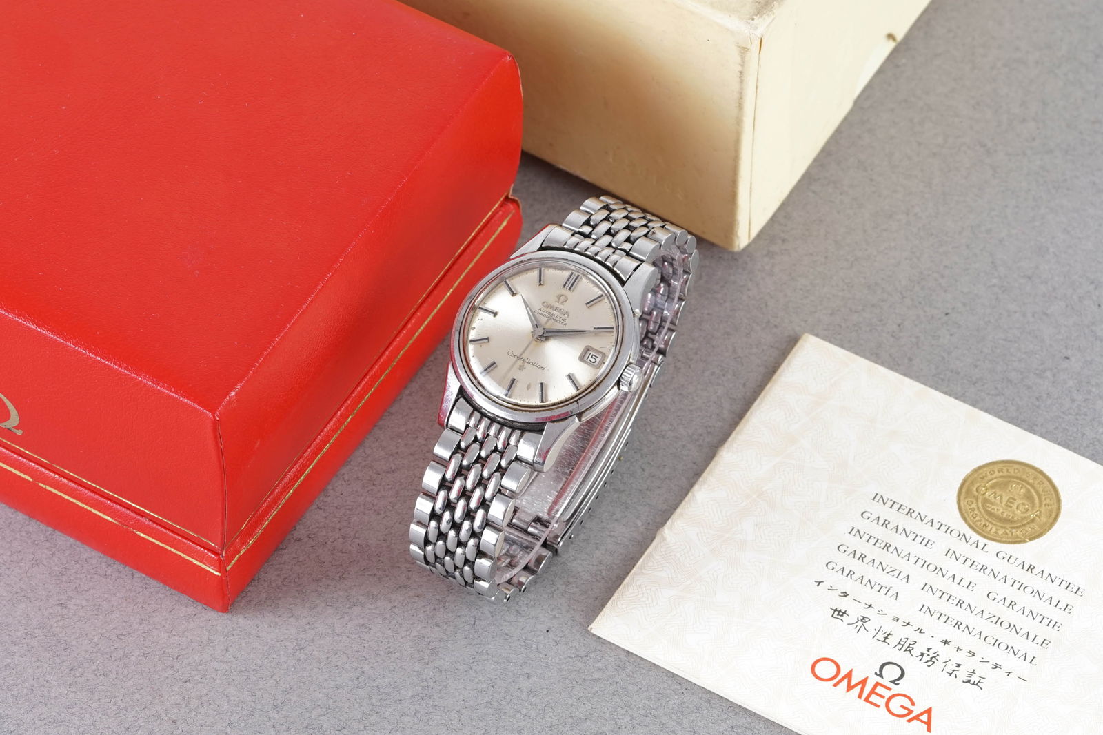 OMEGA CONSTELLATION DATE AUTOMATIC CHRONOMETER W/ BOX & GUARANTEE PAPERS REF. 14393 CIRCA 1965: OMEGA CONSTELLATION DATE AUTOMATIC CHRONOMETER W/ BOX & GUARANTEE PAPERS REF. 14393 CIRCA 1965, this watch is a ref. 14393 and is fitted with a circular patina silver dial with a date window, appl