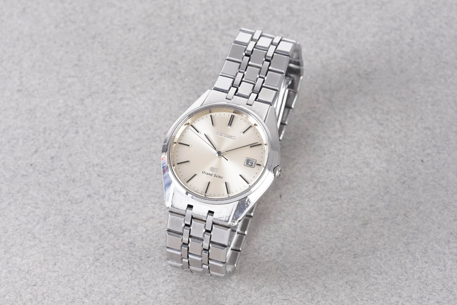 GRAND SEIKO DATE QUARTZ: GRAND SEIKO DATE QUARTZ, this watch is fitted with a circular silver dial with a date window, stick hour markers and hands. The 37mm stainless steel case is fitted with a crown and a case back. Inside