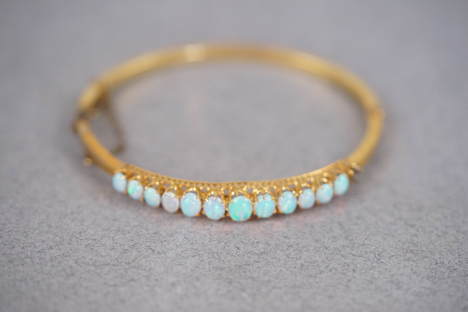 9CT GOLD OPAL BANGLE BRACELET: 9ct gold bangle, gross weight 5.76 gms. 12 cabochon opals, one missing.