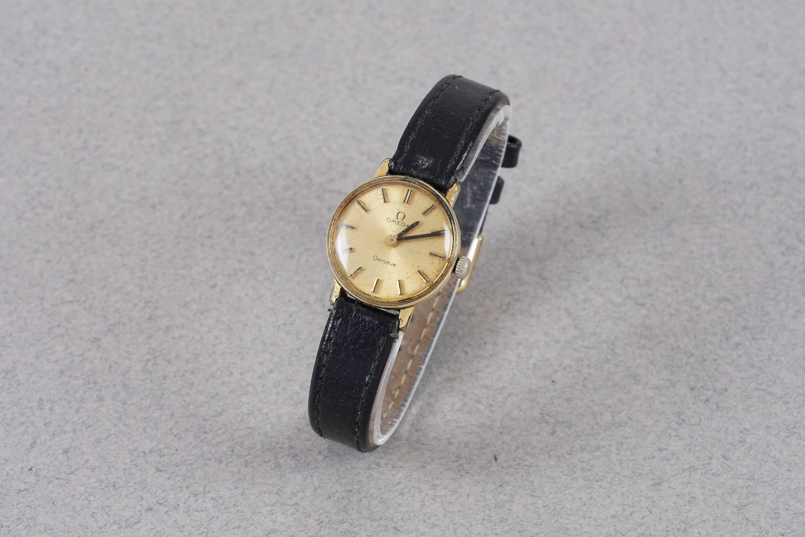 OMEGA GENEVE WRISTWATCH: OMEGA GENEVE WRISTWATCH, this watch and is fitted with a circular gold dial with stick hour markers and pencil hands. The 23mm gold plated case is fitted with a crown and a snap case back. Inside is