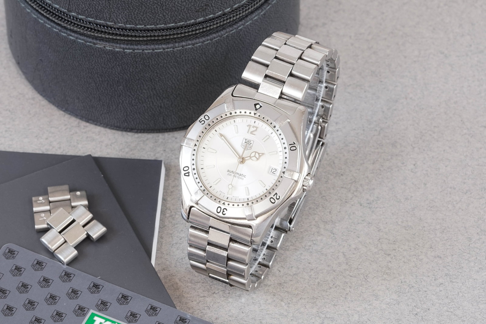 TAG HEUER AUTOMATIC DATE W/ BOX & GUARANTEE CARD REF. WK2116 CIRCA 2002: TAG HEUER AUTOMATIC DATE W/ BOX & GUARANTEE CARD REF. WK2116 CIRCA 2002, this watch is a ref. WK2116 and is fitted with a circular silver dial with a date window, applied luminous hour markers and