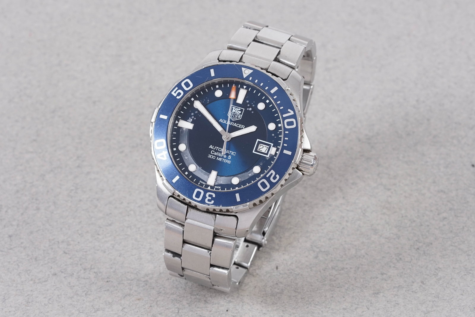 TAG HEUER AQUARACER CALIBRE 5 W/ BOX REF. WAN2111: TAG HEUER AQUARACER CALIBRE 5 W/ BOX REF. WAN2111, this watch is a ref. WAN2111 and is fitted with a circular blue dial with a date window, luminous dot hour markers and hands. The 42mm stainless stee
